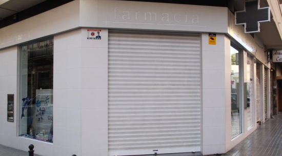 fachada de farmacia con puerta metálica con persiana enrollable